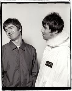 two young men standing next to each other in front of a white wall, one with his mouth open