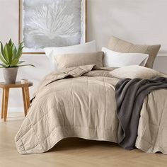 a bed with pillows and blankets on top of it next to a potted plant