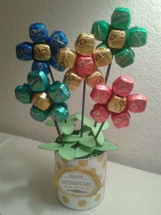 a vase filled with assorted chocolate candies on top of a white table next to a wall