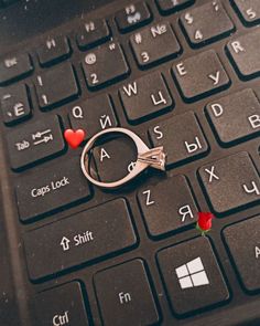 a pair of scissors sitting on top of a computer keyboard with hearts attached to it