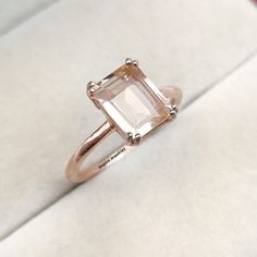 a ring with an emerald cut stone on it sitting on a white cloth covered surface