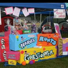 some candy boxes are stacked on top of each other in front of a blue tent