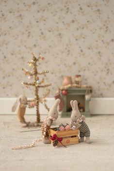 two small mice are sitting in a box next to a christmas tree and wallpaper