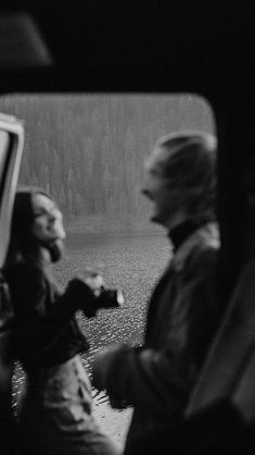 black and white photograph of two people sitting in the back of a car looking at something