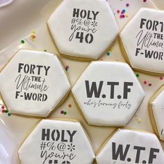 decorated cookies on a plate with words written in black, white and gold icing