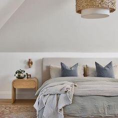 a bedroom with white walls and wooden flooring has a large bed in the middle