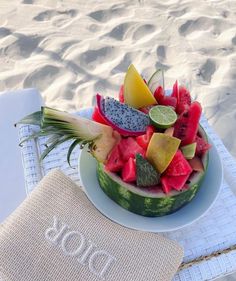 a watermelon and pineapple fruit salad on a beach