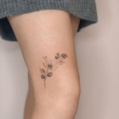 a woman's leg with a small flower tattoo on the left side of her thigh