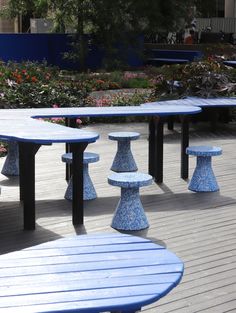 several blue and white benches sitting on top of a wooden deck next to flowers in the background