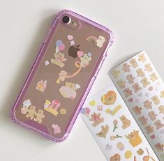 an iphone case with stickers on it next to a book and some other items