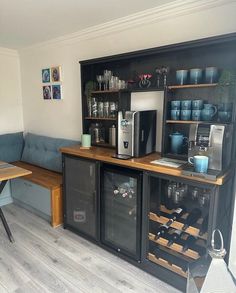 a kitchen area with a table, refrigerator and coffee maker