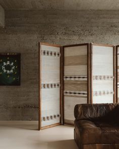 an open room divider in front of a brown leather couch and painting on the wall