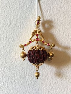 Truly a unique piece of art, inspired by temple jewelry, handcrafted with 22K gold, real uncut rubies, and "The gem of beads", the rudraksha.  Rudrakshas are the dried seeds of a tree that grows predominantly in the Himalayas, at the border between India and Nepal. In the hustle and bustle of today's life, for anyone who is constantly on the move, a rudraksha is believed to create a protective cocoon of your own energy, warding off negativity and untimely events. Scientific research proves that rudrakshas have certain electro-magnetic properties and when worn against the skin, lowers blood pressure, cool the body, strengthens the heart, and brings a certain calmness and alertness to the nervous system. When we wear a rudraksha, we are literally carrying sacks of oxygen, carbon, and hydroge Festive Spiritual Temple Necklace With Latkans, Red Temple Necklace For Gifts, Red Temple Necklace As Gift, Red Temple Jewelry Necklace As A Gift, Red Temple Jewelry Necklace For Gift, Spiritual Chandbali Temple Necklace For Diwali, Festival Pendant Temple Necklace With Latkans, Festival Temple Pendant Necklace With Latkans, Temple Jewelry Tikka For Diwali Gift