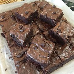 brownies with chocolate frosting sitting on top of parchment paper