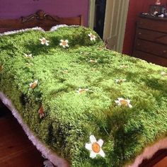 a bed covered in green grass with flowers on it