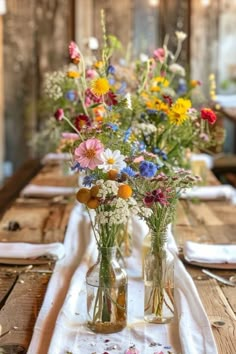 three vases filled with flowers sitting on top of a wooden table