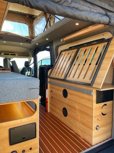 the inside of a van with wood flooring and storage compartments on it's side