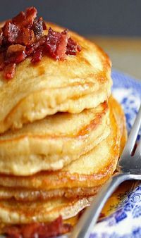 a stack of pancakes with bacon on top