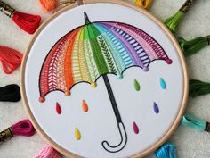 a colorful umbrella is being displayed on a white surface with tassels around it