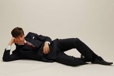 a man in a suit and tie laying on the ground with his hands behind his head