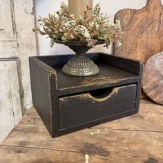 an old wooden box with flowers in it on a table next to a candle holder