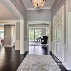 an empty hallway with wood floors and chandelier