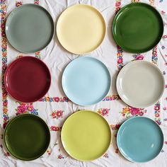 six different colored plates on a table cloth