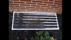 a radiator sitting on the ground in front of a brick wall next to a plant