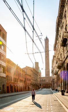 a person walking down an empty street in the middle of town with power lines overhead