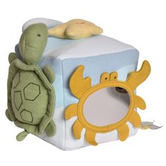 a stuffed turtle is sitting on top of a toy block with a mirror in the shape of a cube