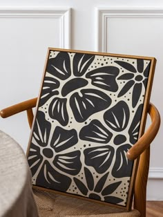 a black and white painting sitting on top of a wooden chair next to a table