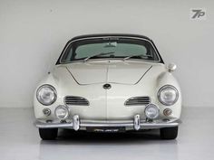 an old white sports car parked in a garage