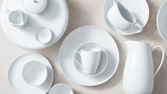 white dishes and cups are arranged on the table