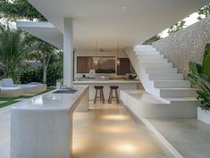 the interior of a modern house with white walls and stairs leading up to an outdoor kitchen