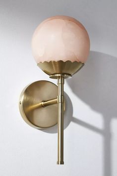 a light that is on the wall next to a white wall with a pink ball