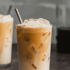 two glasses filled with iced coffee sitting on top of a table