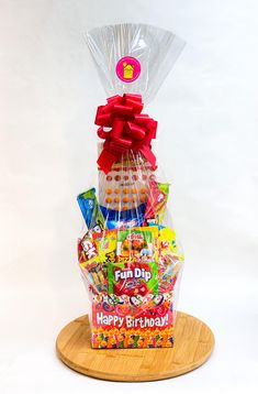 a birthday gift basket with candy and candies on a wooden platter in front of a white background