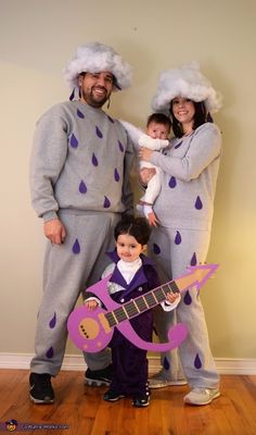 two adults and a child in costumes standing next to each other, one holding a guitar