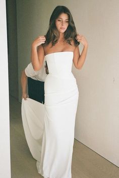 a woman in a white dress is posing for the camera with her hand on her hip