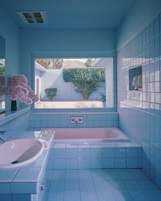 a bath room with a tub a sink and a large window in it's center