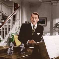 a man in a suit and tie sitting at a desk with music sheets on it