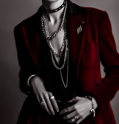 a woman in a red jacket and necklaces is posing for the camera with her hands on her hips