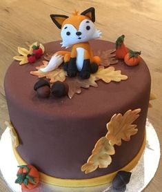 a cake decorated with an image of a fox on top of leaves and acorns