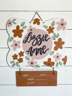 a wooden sign that says abbie ame with flowers on it and a name tag hanging from the front