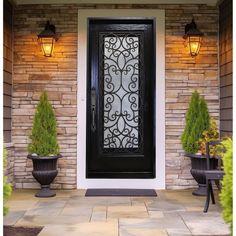 a black front door with two planters on either side and an iron screen in the middle