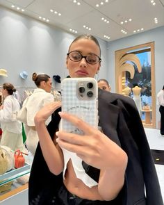 a woman taking a selfie with her cell phone in front of the camera at an event