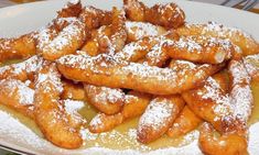 powdered sugar covered pastries are on a white plate with yellow liquid in the middle