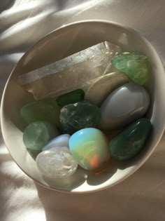 a white bowl filled with lots of different colored rocks and stones on top of a table