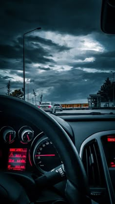 the dashboard of a car on a highway with dark clouds in the sky behind it