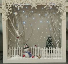 a snowman is sitting in front of a white picket fence with trees and lights